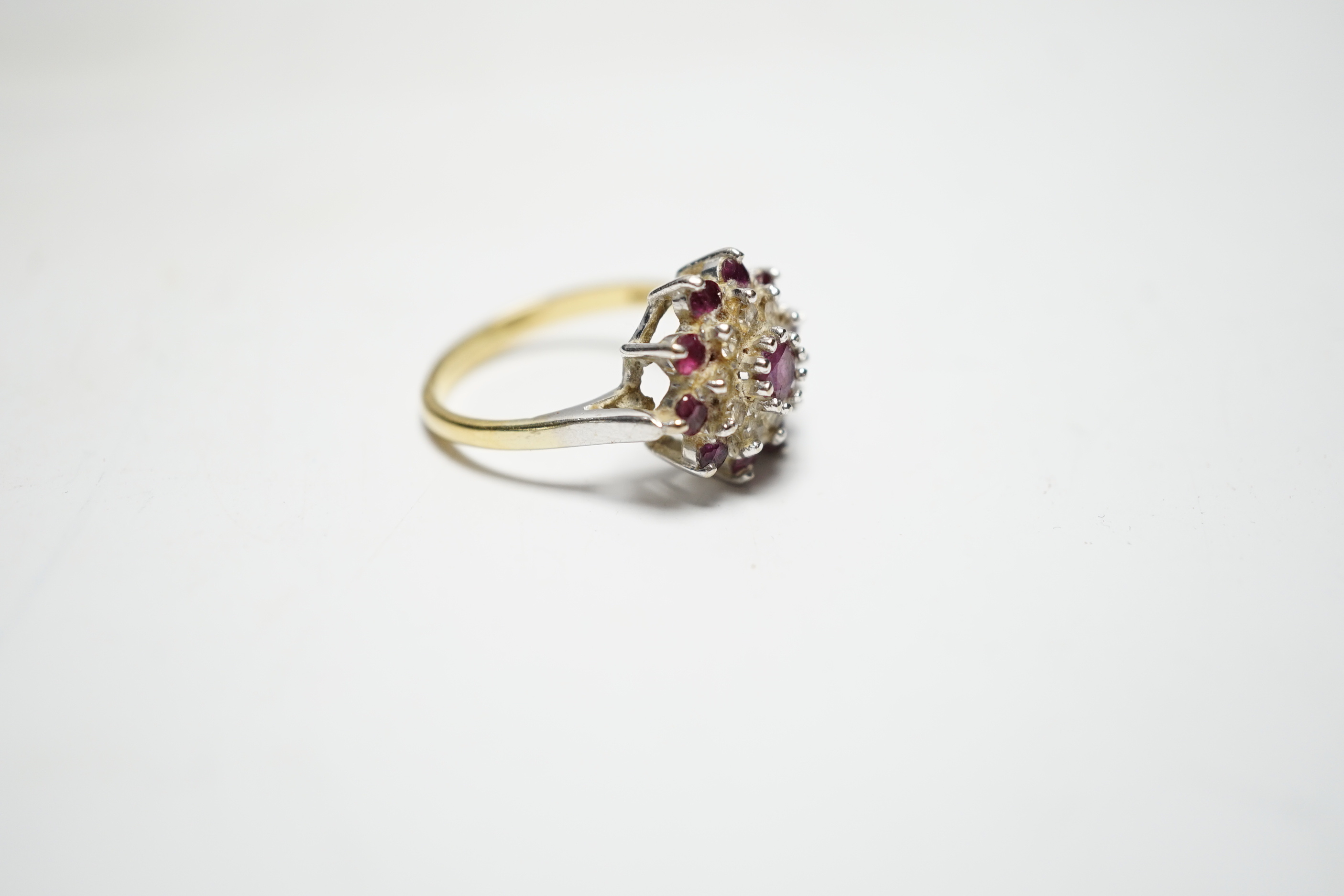 A modern 18ct gold, ruby and diamond set flowerhead cluster ring, size O, gross weight 5.2 grams.